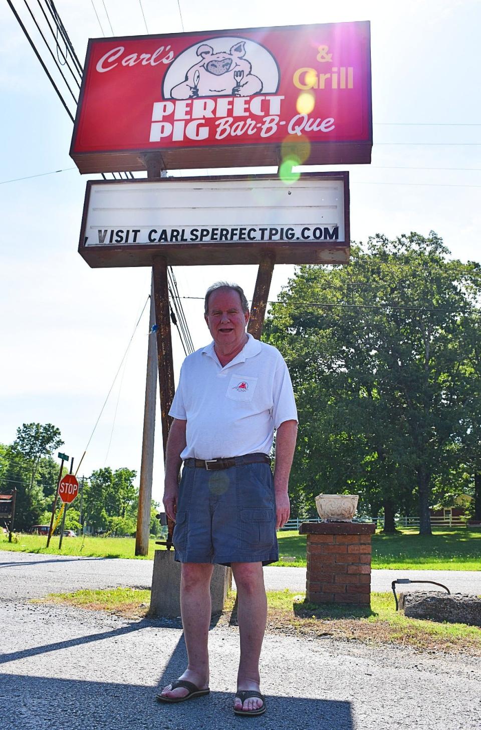 Carl Teitloff stands in front of the Carl's Perfect Pig sign the week after he retired.