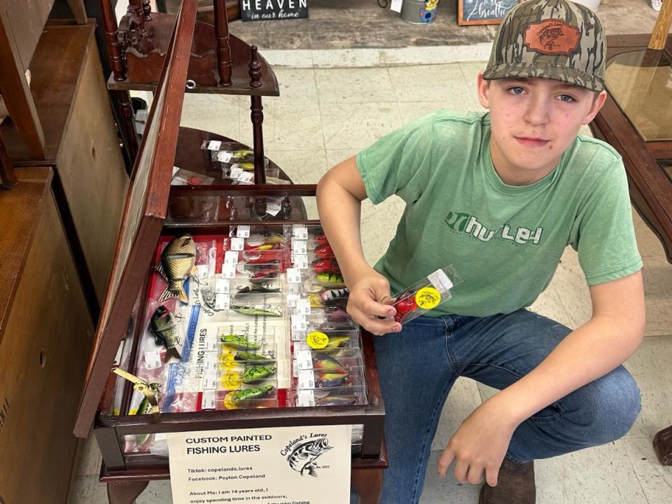 Peyton Copeland, 14, of Barlow poses by a display case of his hand-painted fishing lures he sells under the brand Copeland's Lures.