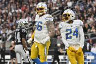 Los Angeles Chargers defensive end Morgan Fox (56) and safety Nasir Adderley (24) reacts after a fumble recovery and Las Vegas Raiders wide receiver Keelan Cole (84) looks on during the first half of an NFL football game, Sunday, Dec. 4, 2022, in Las Vegas. (AP Photo/David Becker)