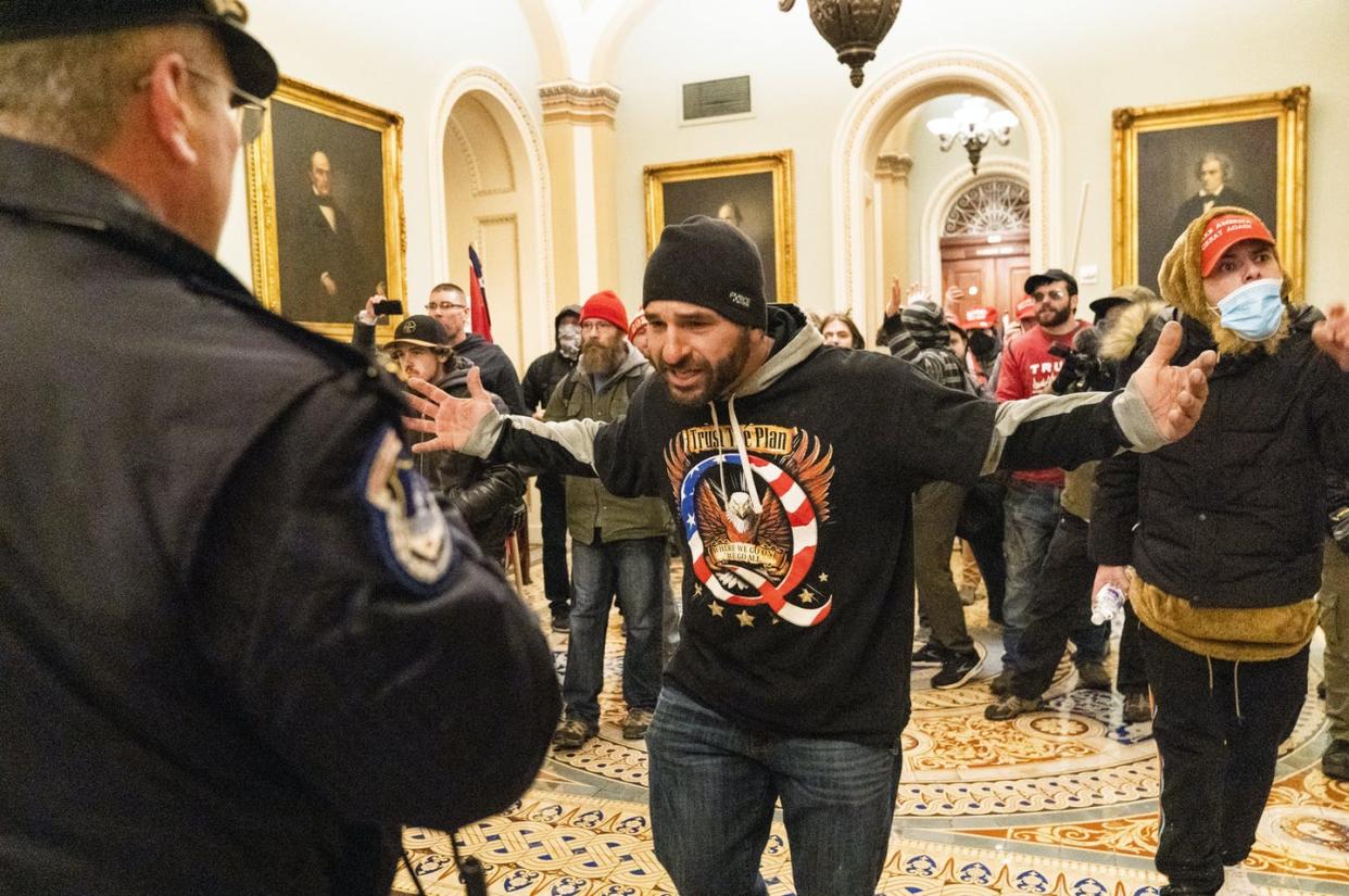 <span class="caption">A supporter of President Donald Trump, seen wearing a QAnon shirt, is confronted by Capitol Police officers outside the Senate Chamber during the invasion of the U.S. Capitol. </span> <span class="attribution"><span class="source">(AP Photo/Manuel Balce Ceneta)</span></span>