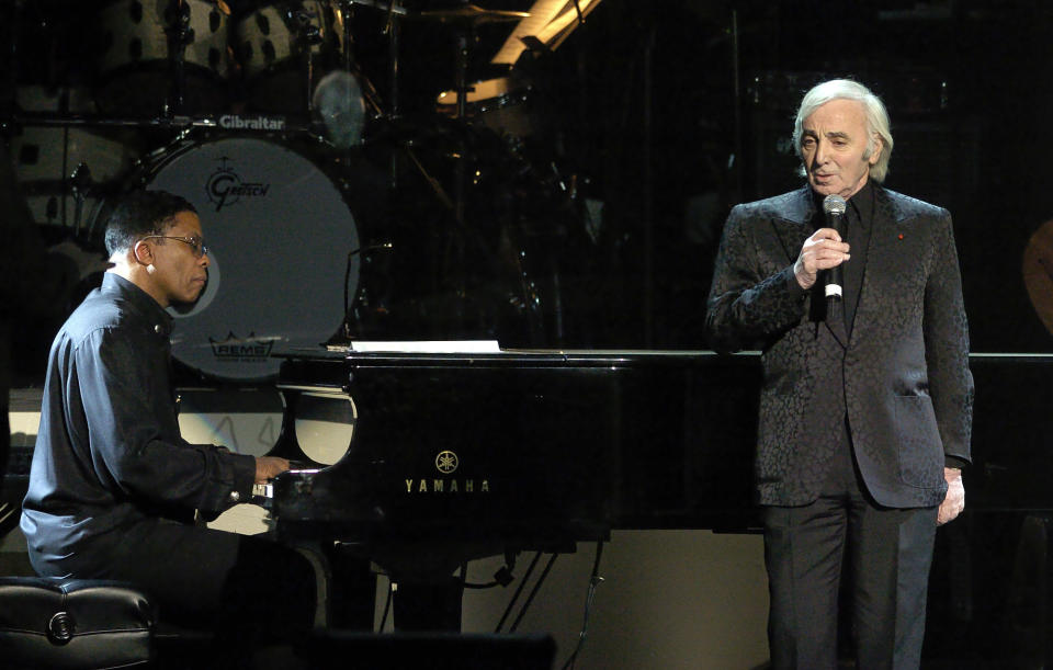 FILE - In this Feb. 6, 2004 file photo, singer Charles Aznavour, right, performs as Herbie Hancock plays piano during the MusiCares 2004 Person of the Year Tribute to Sting, in Culver City, Calif. Charles Aznavour, the French crooner and actor whose performing career spanned eight decades, has died. He was 94. (AP Photo/Mark J. Terrill, File)