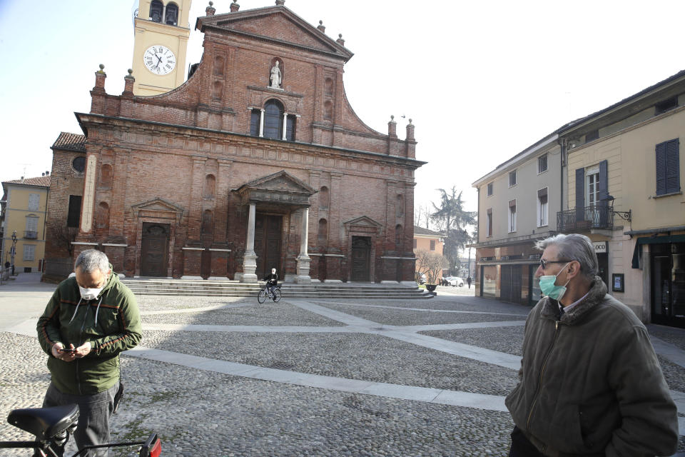 People wear masks as they stand in front of the San Biagio church in Codogno, near Lodi, Northern Italy, Saturday, Feb. 22, 2020. A dozen towns in northern Italy are on effective lockdown after the new virus linked to China claimed a first fatality in Italy and sickened an increasing number of people. The secondary contagions have prompted local authorities in towns of Lombardy and Veneto to order schools, businesses, and restaurants closed, and to cancel sporting events and Masses. (AP Photo/Luca Bruno)