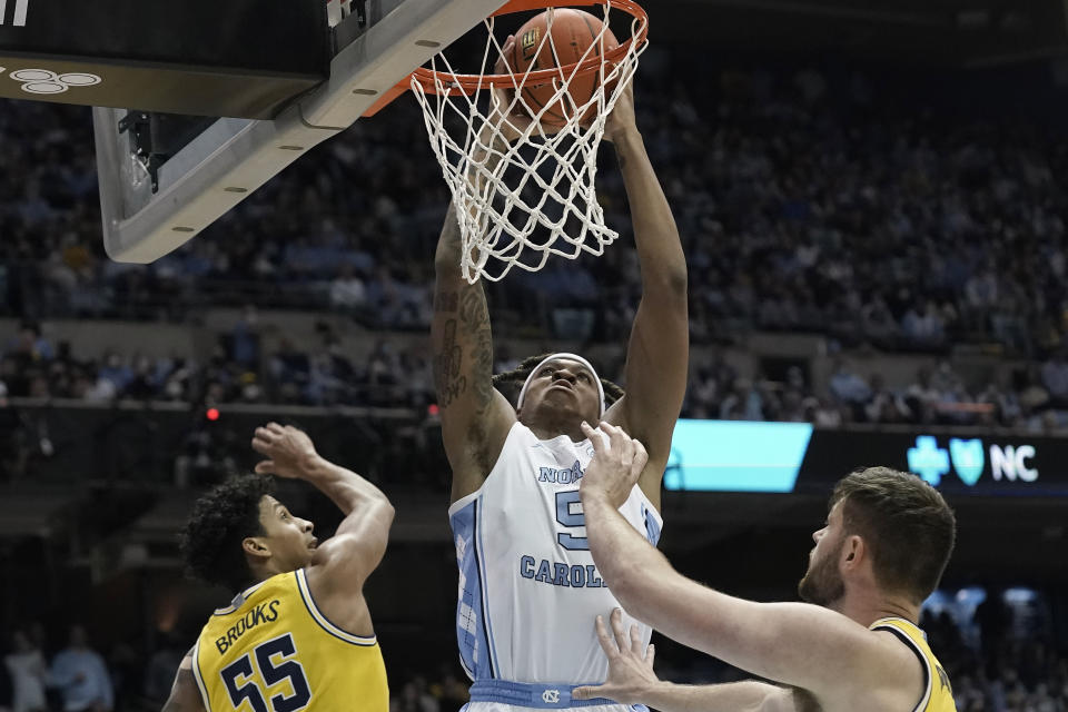 North Carolina forward Armando Bacot (5) dunks while Michigan guard Eli Brooks (55) and center Hunter Dickinson look on during the first half of an NCAA college basketball game in Chapel Hill, N.C., Wednesday, Dec. 1, 2021. (AP Photo/Gerry Broome)