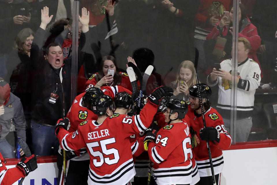 Chicago Blackhawks left wing Alex DeBrincat (12) celebrates with teammates after scoring the game-winging goal against the Nashville Predators during the overtime period of an NHL hockey game in Chicago, Friday, Feb. 21, 2020. (AP Photo/Nam Y. Huh)