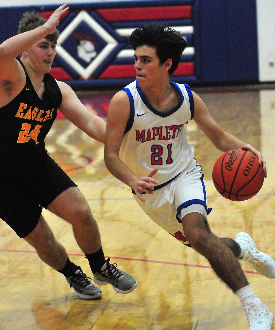 Mapleton High School’s Scotty Hickey (21) drives the ball around Monroeville High School’s Ian Schafer (24) during basketball action at Mapleton High School Friday, Jan. 21, 2022.