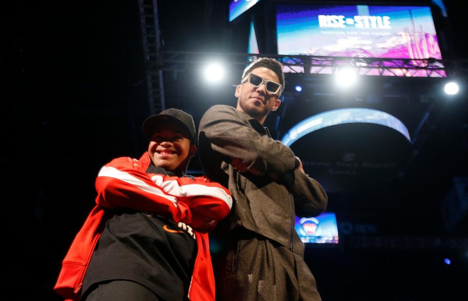 Suns' Devin Booker walks the runway with Marcus Hodge during "Rise in Style," a charity fashion show at Talking Stick Resort Arena in Phoenix, Ariz. on January 11, 2020. 