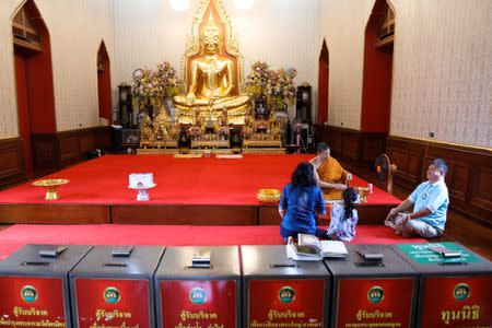 Tourists pray as donation boxes are seen at a temple in Bangkok, Thailand, Octoboer 18, 2017. Picture taken October 18, 2017. REUTERS/Athit Perawongmetha