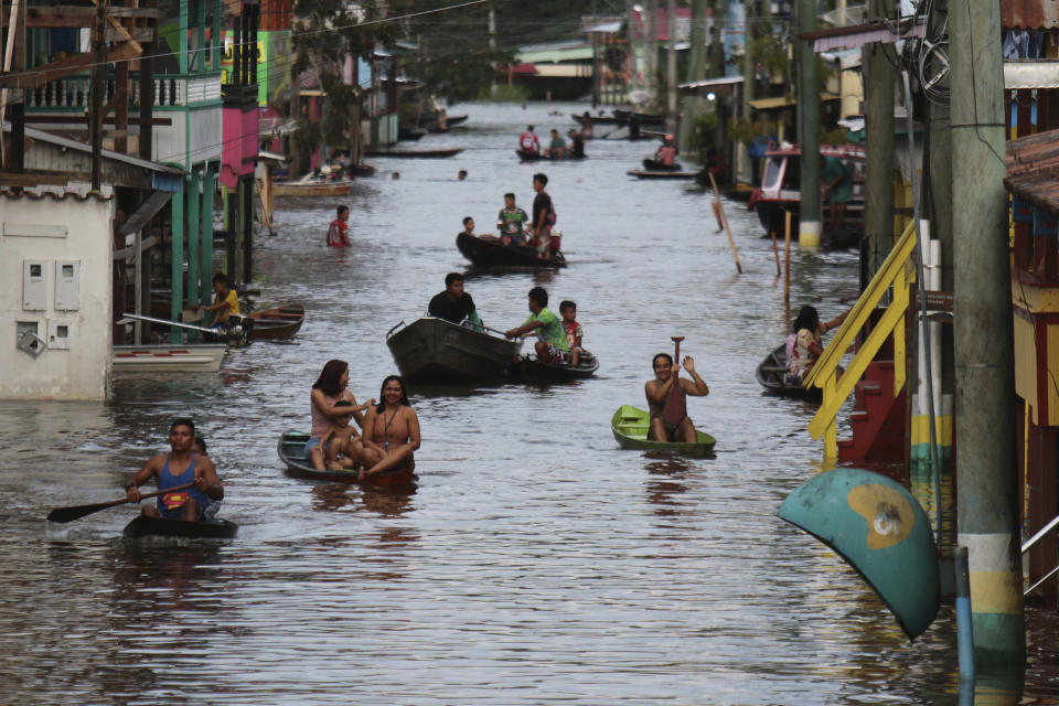 Residents navigate a flooded street in Anama, Amazonas state, Brazil, Thursday, May 13, 2021. (AP Photo/Edmar Barros)