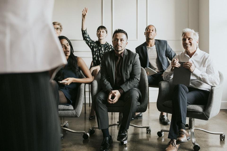 Business people in a seminar raising their hands 