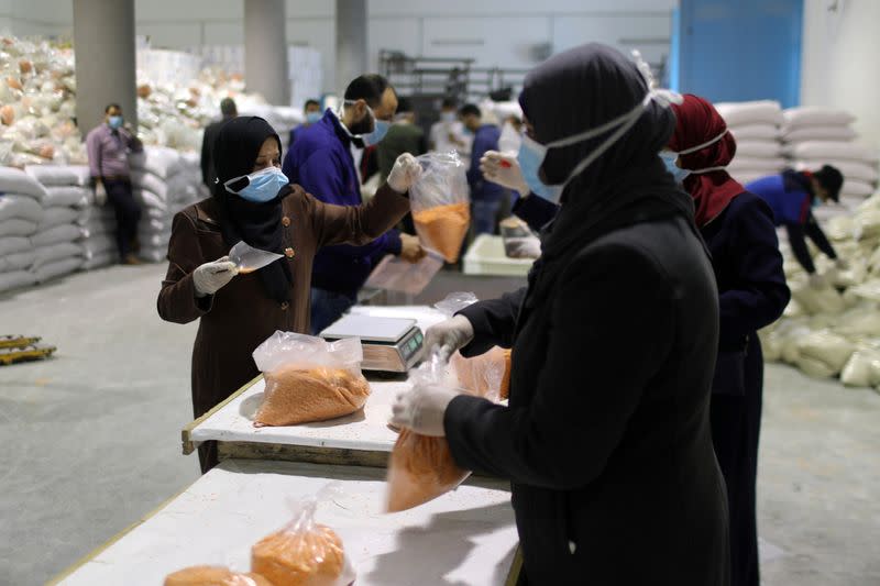 Workers pack food supplies to be distributed and delivered by UNRWA to the homes of Palestinian refugees in the northern Gaza Strip