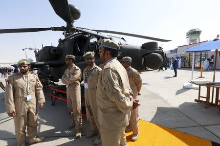 UAE Air Force soldier stand beside an Apache helicopter during Dubai Airshow November 8, 2015. REUTERS/Ahmed Jadallah