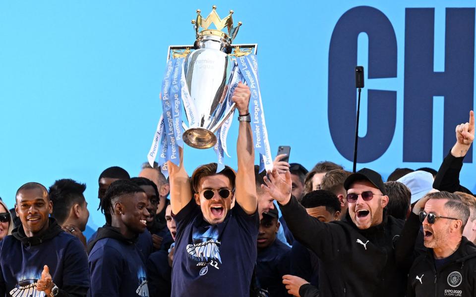 Manchester City's English midfielder Jack Grealish (C) holds up the trophy at an event for fans with members of the Manchester City football team following an open-top bus parade through Manchester, north-west England on May 23, 2022, to celebrate winning the 2021-22 Premier League title. - GETTY IMAGES