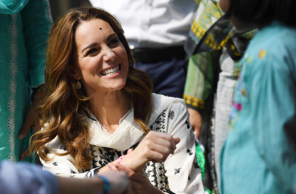 The Duke of Cambridge watches as his wife, the Duchess of Cambridge, receives a bracelet during a visit to the SOS Village at Lahore in Pakistan (Photo by Neil Hall/PA Images via Getty Images)