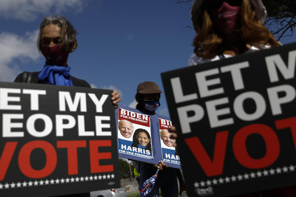 FILE - In this Nov. 1, 2020, file photo, people carry signs supporting voting rights and former Vice President Joe Biden, during a "Souls to the Polls" march in Model City, Miami. A tough road lies ahead for Biden who will need to chart a path forward to unite a bitterly divided nation and address America’s fraught history of racism that manifested this year through the convergence of three national crises. (AP Photo/Rebecca Blackwell, File)