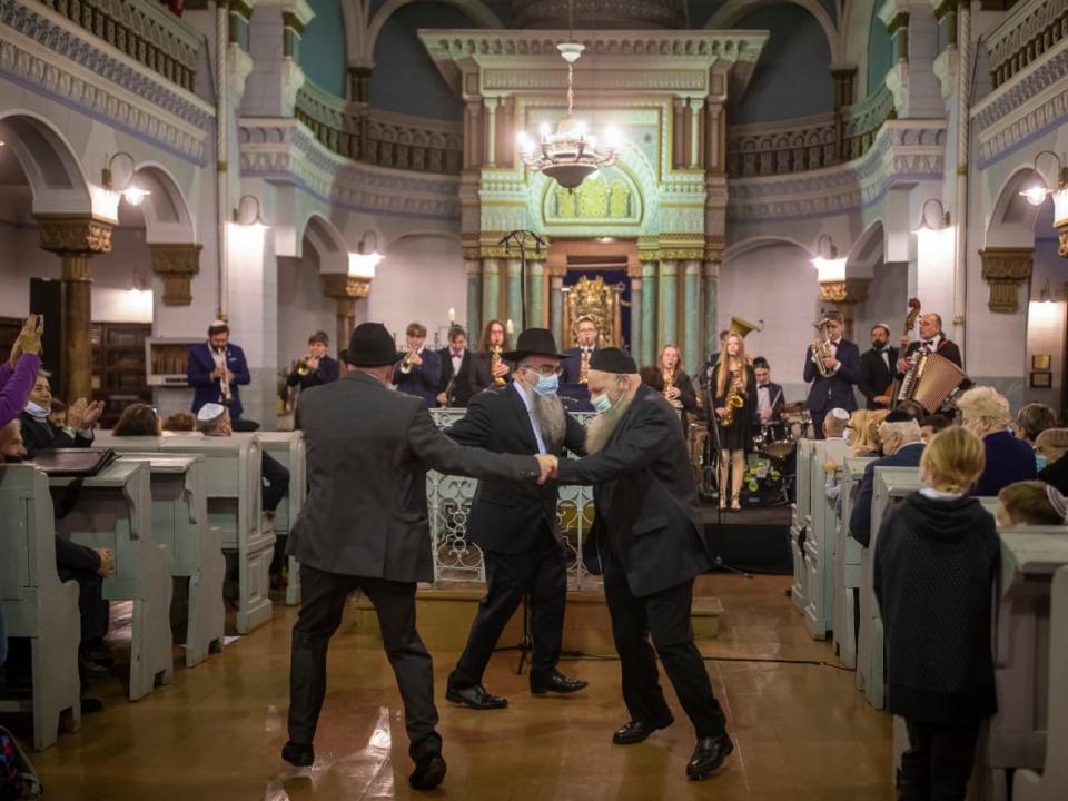 Men in masks dance during the Jewish holiday of Hanukkah at the synagogue in Vilnius, Lithuania last weekend. (Mindaugas Kulbis/The Associated Press - image credit)