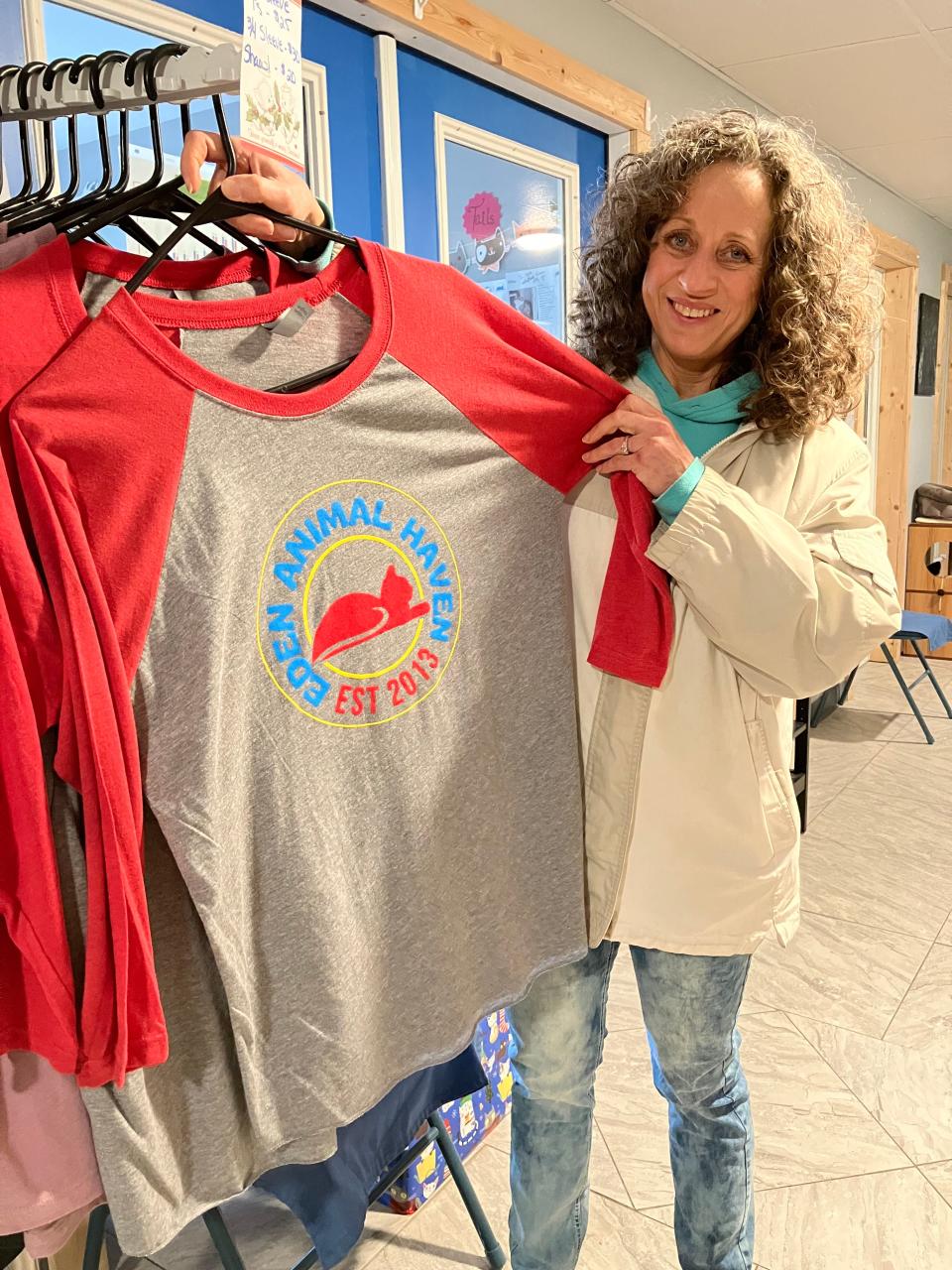 Leslie Sawyer, director of Eden Animal Haven, stands with a shirt bearing the shelter’s new logo. The shirts are on sale for $25 in short sleeves and $30 in three-quarter-length sleeves.