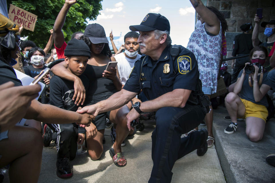 Ypsilanti, Michigan Police Chief Tony DeGiusti shakes hands with a protestor while taking a knee with demonstrators in a moment of solidarity during a police brutality protest in downtown Ypsilanti, Mich., Saturday, June 6, 2020. ( Jenna Kieser/Ann Arbor News via AP)
