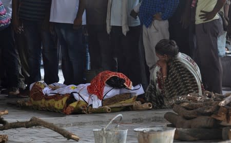 A relative mourns next to the body of a woman who died during a highway collision in which another woman, who is fighting a rape case against a legislator of the ruling Bharatiya Janata Party (BJP) was critically injured, in Unnao
