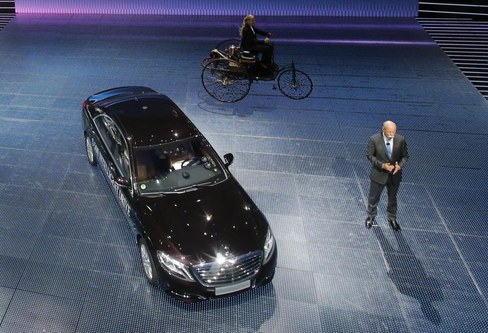 Daimler Chief Executive Dieter Zetsche presents the Mercedes S500 Intelligent Drive car, the first self-steered Mercedes, during its world premiere on media night at the Frankfurt motor show September 9, 2013. The world's biggest auto show is open to the public September 14 -22. At rear, a woman drives a replica of the Benz Patent-Motorwagen, widely regarded as the world's first motor-driven vehicle from 1866. REUTERS/Wolfgang Rattay (GERMANY - Tags: BUSINESS TRANSPORT)