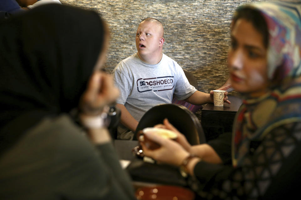 In this Monday, Aug. 6, 2018, photo, cafe staff Ali Bakhti, 22, center, with down syndrome talks to his colleagues in Downtism Cafe in Tehran, Iran. The popular cafe, whose name combines “Down” with “autism,” in Tehran’s bustling Vanak Square is entirely run by people with Down syndrome or autism. More than just providing meaningful work, the cafe is helping break down barriers by highlighting how capable people with disabilities are. (AP Photo/Ebrahim Noroozi)