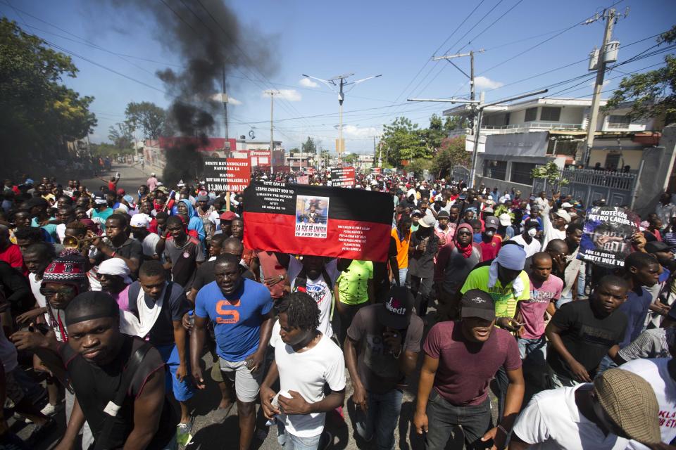 Demonstrators hold up a former Haitian flag with a picture of independence hero Jean Jacques Dessallines, during a protest demanding to know how Petro Caribe funds have been used by the current and past administrations, in Port-au-Prince, Haiti, Wednesday, Oct. 17, 2018. Much of the financial support to help Haiti rebuild after the 2010 earthquake comes from Venezuela's Petro Caribe fund, a 2005 pact that gives suppliers below-market financing for oil and is under the control of the central government. (AP Photo/Dieu Nalio Chery)