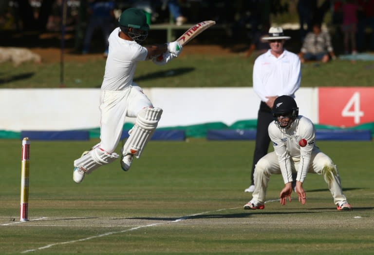 Zimbabwe's batsman Sikanda Raza Butt (L) hits the ball past New Zealand's Henry Nicholls during the third day of the first Test in Bulawayo on July 30, 2016