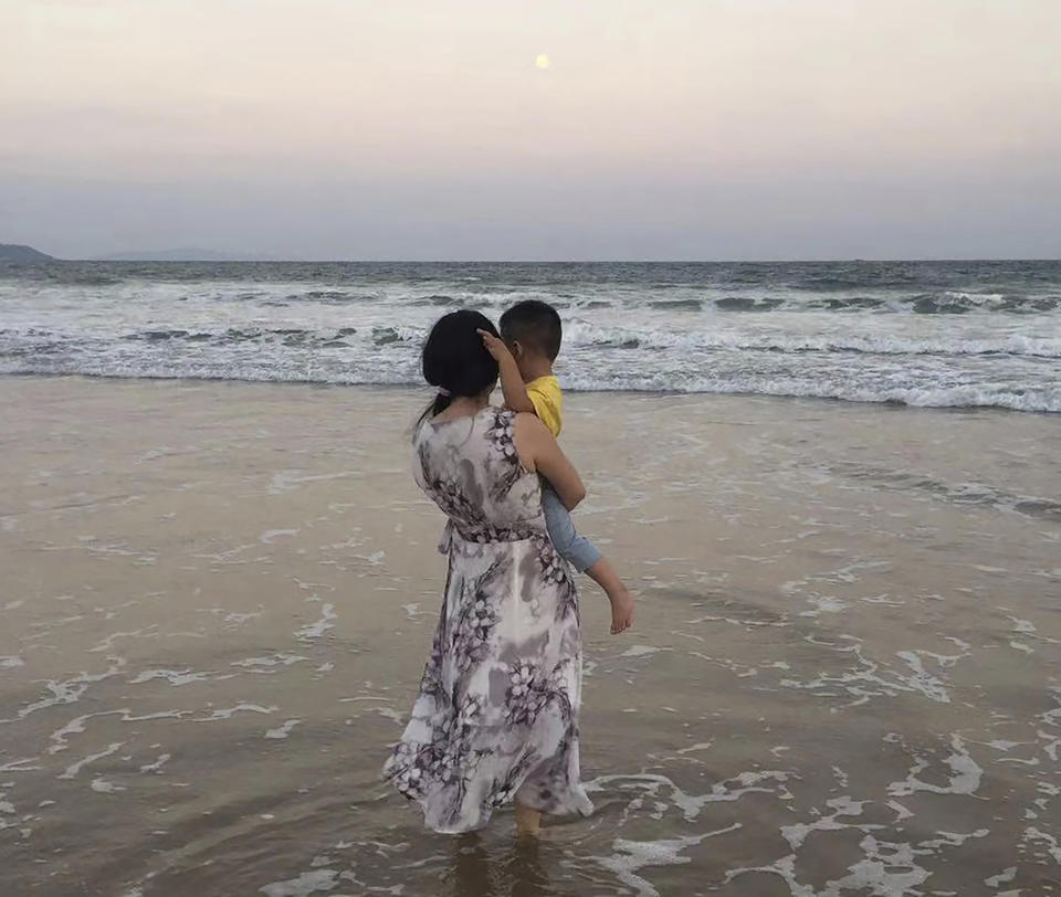 In this photo released by Zou Xiaoqi, Zou Xiaoqi, a single mother turned activist in Shanghai, holds her son as they visit a beach in Sanya, southern China's Hainan province in October, 2019. Zou, who has become a source of support for single moms ever since she started publicly campaigning for her maternity benefits, said that the cultural stigma around being a single mother is still very intense. (Zou Xiaoqi via AP)