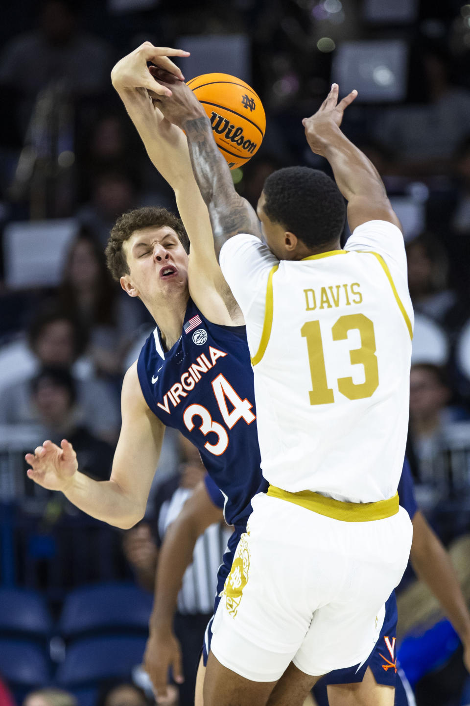 Virginia's Jake Groves (34) defends Notre Dame's Tae Davis (13) during the first half of an NCAA college basketball game on Saturday, Dec. 30, 2023, in South Bend, Ind. (AP Photo/Michael Caterina)