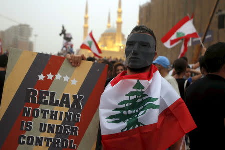 A protester wears a mask and holds a sign during a protest against perceived government failures, including a rubbish disposal crisis, at Martyrs' Square in downtown Beirut, Lebanon September 9, 2015. REUTERS/Mohamed Azakir