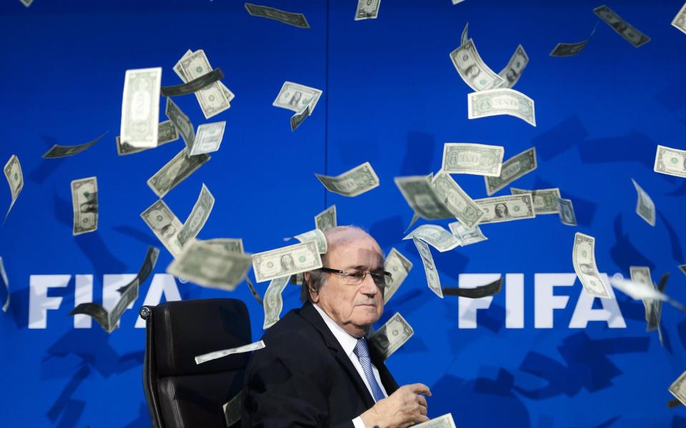 Fifa president Sepp Blatter looks on as fake dollar notes fly around him
