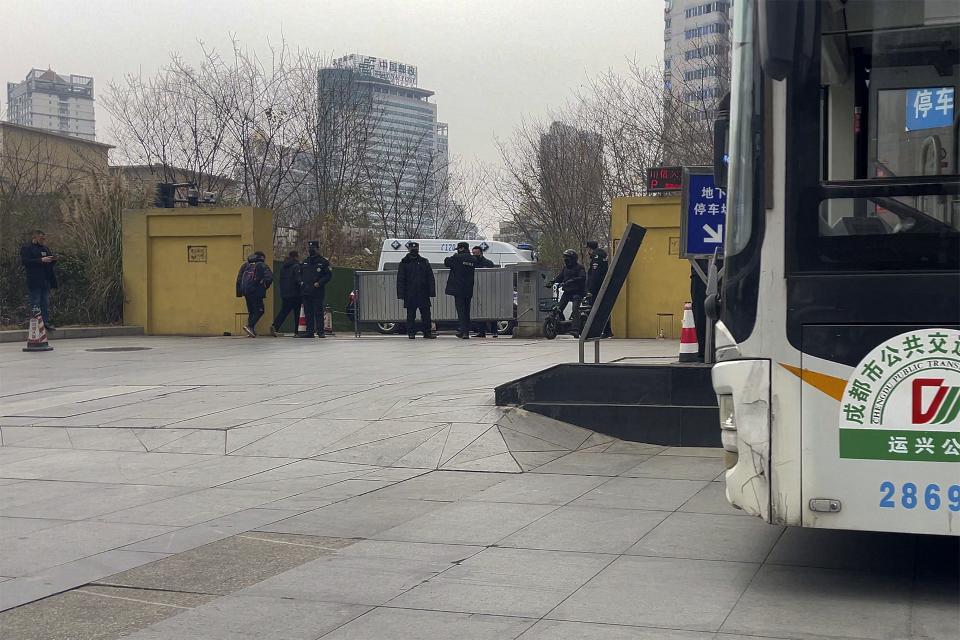 Plainclothes policemen and security personnel stand watch at an entrance gate to the Sichuan Trust office building in Chengdu in southwestern China's Sichuan Province on Feb. 27, 2024. Some investors in a troubled trust fund in China are facing financial ruin under a government plan to return a fraction of their money, casualties of a slump in the property industry and a broader economic slowdown. (AP Photo/Andy Wong)