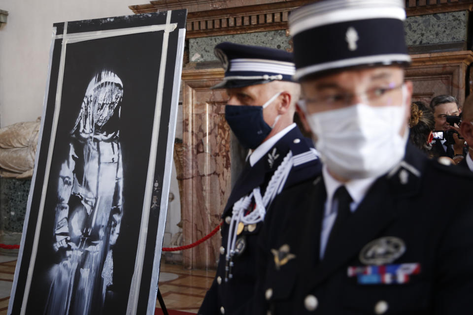 A recovered stolen artwork by British artist Banksy, depicting a young female figure with a mournful expression, that was painted as a tribute to the victims of the 2015 terror attacks at the Bataclan music hall in Paris, is shown during a ceremony at the French Embassy in Rome, Tuesday, July 14, 2020. (AP Photo/Domenico Stinellis)