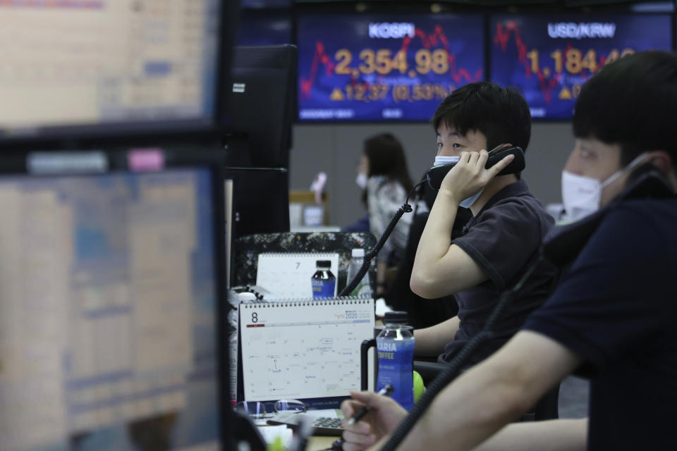 Currency traders talk on phones at the foreign exchange dealing room of the KEB Hana Bank headquarters in Seoul, South Korea, Friday, Aug. 7, 2020. Asian shares were mostly lower Friday in lackluster trading, as the region weighed continuing trade tensions over China and optimism about more fiscal stimulus for the ailing U.S. economy. (AP Photo/Ahn Young-joon)