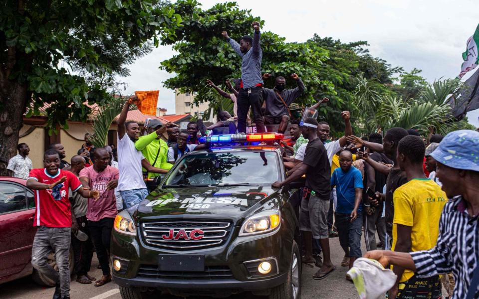 Protesters stand on a vehicle that is part of a military convoy sent to enforce the curfew - BENSON IBEABUCHI/AFP