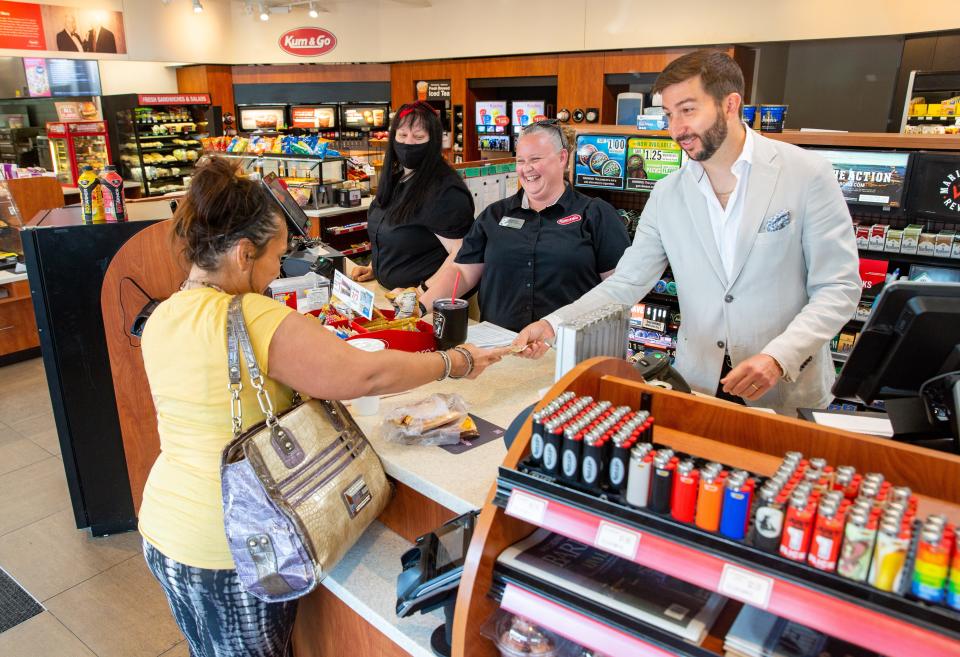 Kum & Go CEO Tanner Krause helps a customer during a store visit in 2021.
