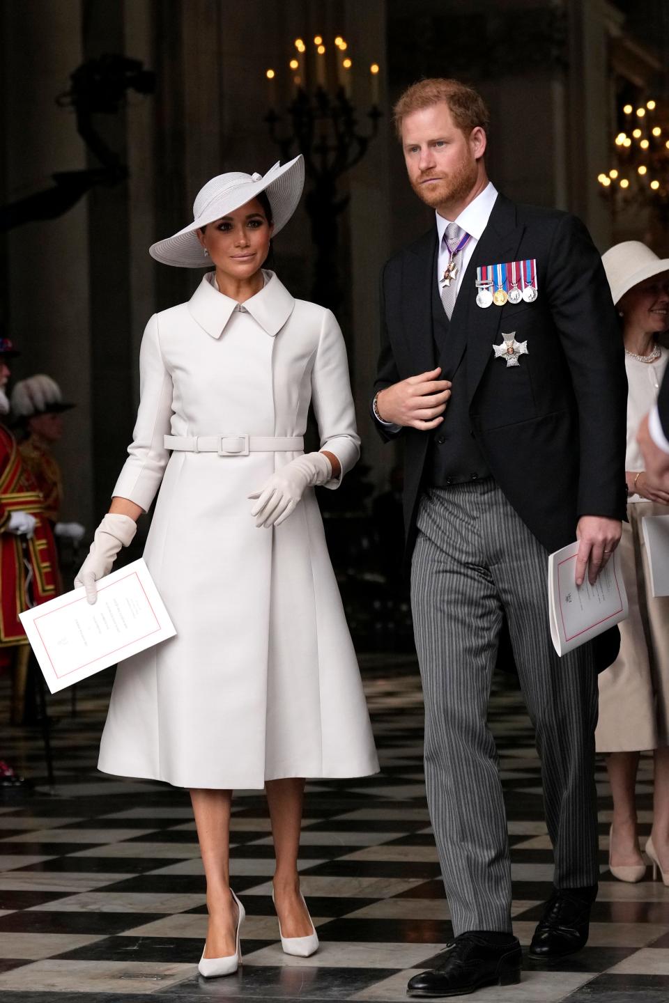Prince Harry and Duchess Meghan of Sussex leave after a service at St Paul's Cathedral in London, on the second day of the Platinum Jubilee celebration of the 70-year reign of Queen Elizabeth II. Meghan wore a grey/beige ensemble featuring a Dior trench coat and a Dior straw hat.