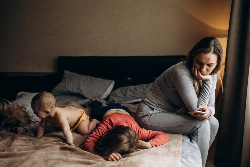 A mom is with her kids on the bed