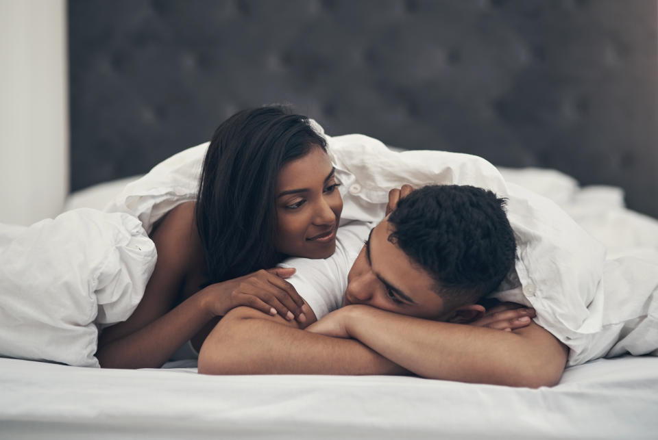 Man and woman lie under a duvet