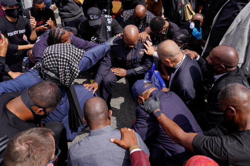 LOS ANGELES, CA - JUNE 02: Los Angeles Police Department Commander Gerald Woodyard joins in taking a knee with protesters and clergy members from the Los Angeles area in a march in downtown Los Angeles near LA City Hall and LAPD Headquarters Tuesday, June 02, 2020 in Los Angeles, CA. Protests have erupted across the country, with people outraged over the death of George Floyd, a black man killed after a white Minneapolis police officer pinned him to the ground with his knee. (Kent Nishimura / Los Angeles Times)