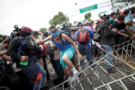 Honduran migrants, part of a caravan trying to reach the U.S., topple a fence after storming the Guatemala border in Ciudad Hidalgo, Mexico October 19, 2018. REUTERS/Ueslei Marcelino