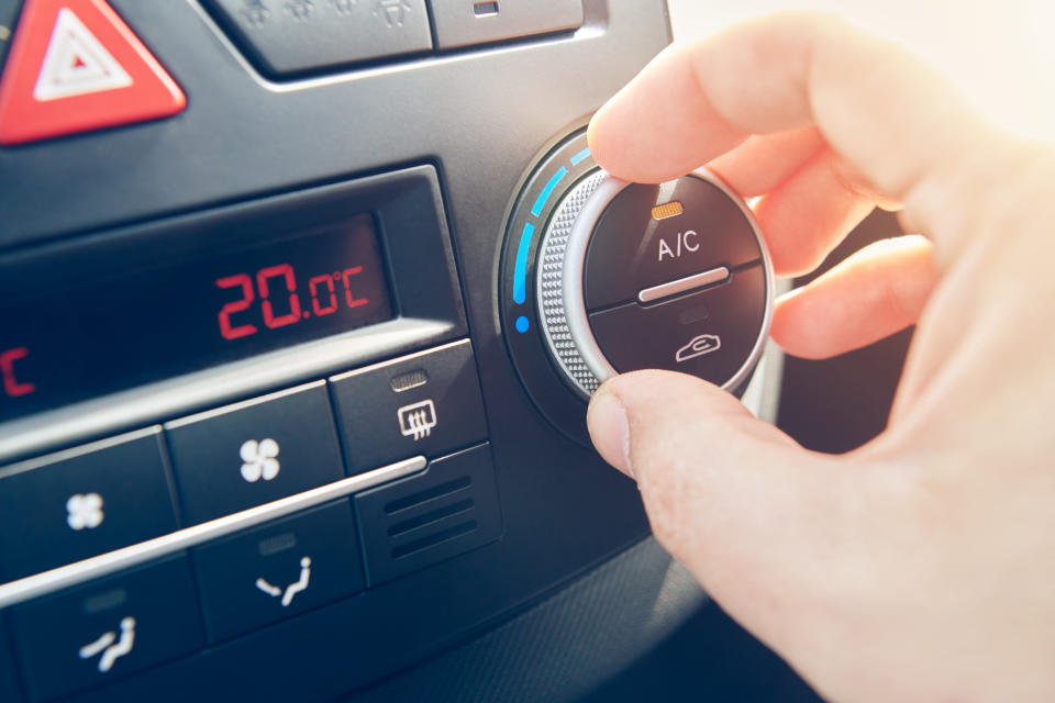 Man hand set the temperature of air conditioner in the car. Driver turning on car climate control system. travel by car. Close up view with selective focus.