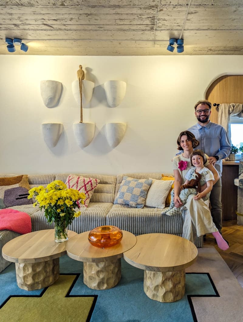 Parents posing with their child in a modern eclectic living room with concrete ceiling