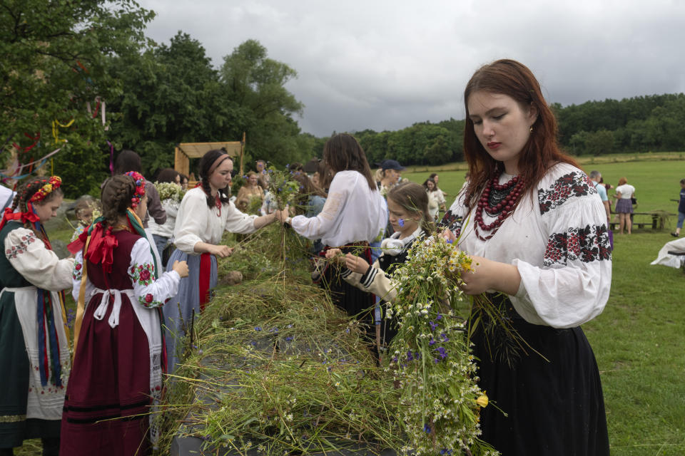 Young girls in traditional clothing weave ritual garland headdress during a traditional Midsummer Night celebration near capital Kyiv, Ukraine, Sunday, June 23, 2024. The age-old pagan festival is still celebrated in Ukraine amid the third year of Russia-Ukraine war. (AP Photo/Efrem Lukatsky)