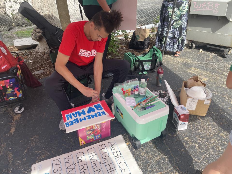 Cameron Jovlin paints a canvas at a vigil for Romen Phelps in West Palm Beach on Saturday.