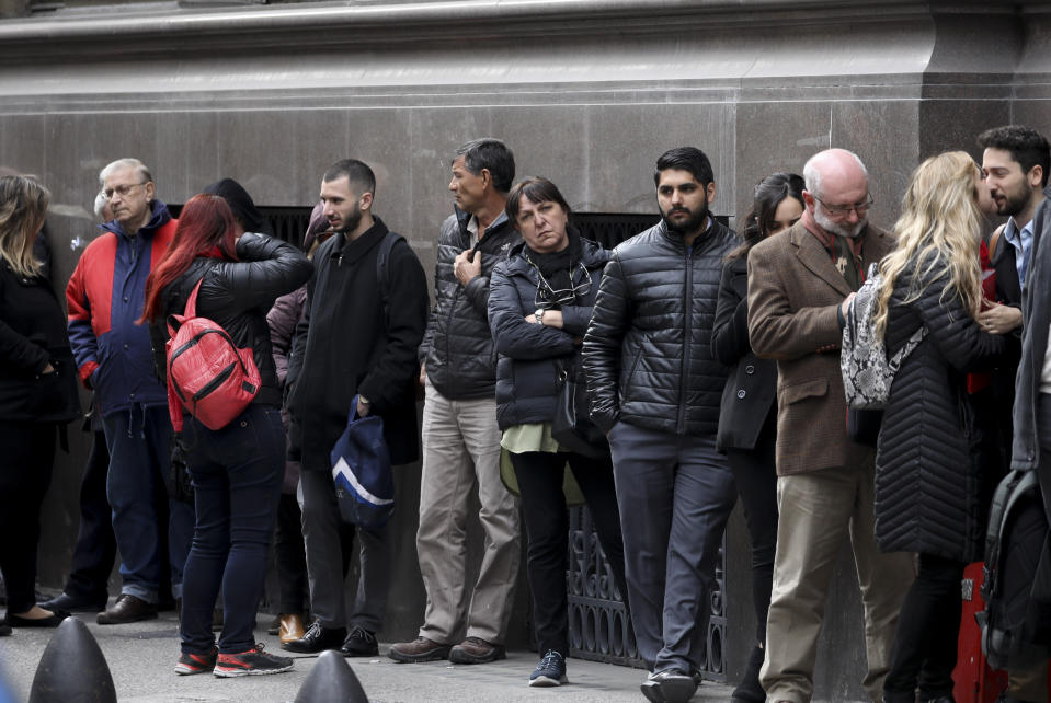 People wait for a bank to open in Buenos Aires, Argentina, Monday, Sept. 2, 2019. Argentina's government on Sunday decreed that Argentines will need authorization from the central bank to buy U.S. dollars in some cases and make transfers abroad for the rest of the year as it tries to prop up its peso currency. (AP Photo/Natacha Pisarenko)