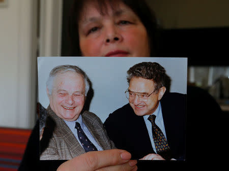 Maria Vasarhelyi, a Hungarian sociologist and opposition activist, holds a picture of billionaire philanthropist George Soros with her late father Miklos Vasarhelyi, who led the Soros Foundation in Hungary in the 1980s and 1990s, in Budapest, Hungary, March 3, 2017. Picture taken March 3, 2017. REUTERS/Laszlo Balogh