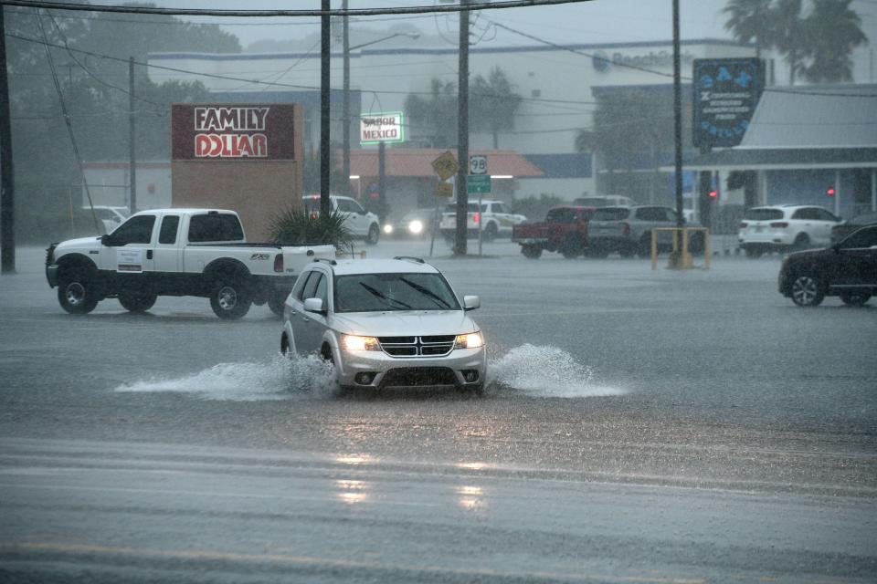 A car makes its way across a flooded parking lot near the intersection of Eglin Parkway and Hollywood Boulevard Thursday afternoon.