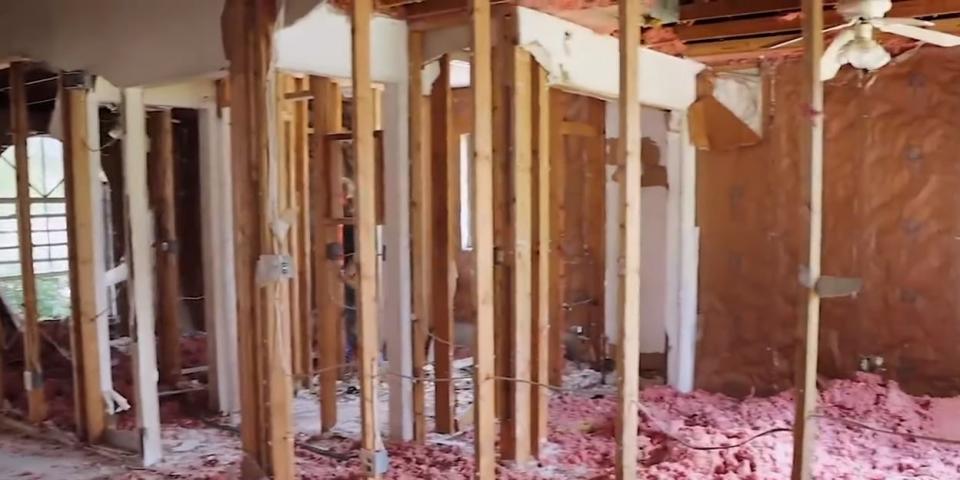 A picture of a house down to its studs with pink material on the floor.