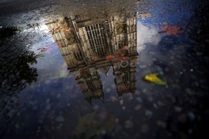 Westminster Abbey is reflected into a puddle in London