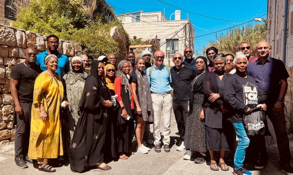 Rami Nashashibi, center in black shirt and pants, next to political scientist Bashir Bashir, in blue, with their interfaith group visiting on Sept. 29, 2023, the village Ein Karem, outside Jerusalem. They're standing in front of the home where Nashashibi's grandparents were displaced from in 1948.